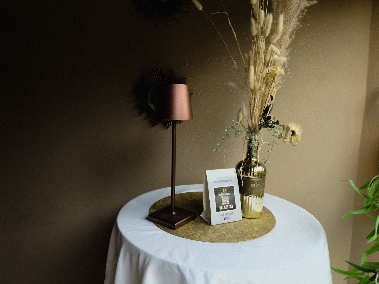 Tavolo con lampada, fiori secchi e menu con QR code del Chillout Zone di Imperia, aperitivo e cocktail