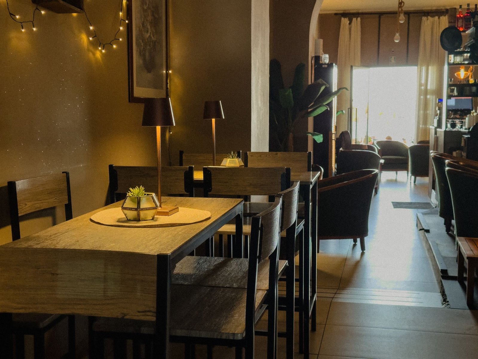 Interno del Chillout Zone a Imperia: tavoli alti in legno con lampade da tavolo dorate e luci soffuse per aperitivo e cena